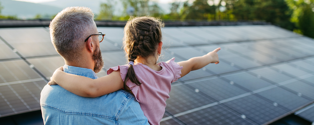Man holding girl pointing at solar panels