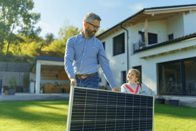 Man and his daughter holding a solar panel