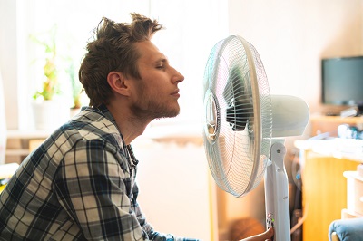 Man cooling off with a room fan