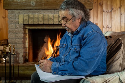 Elderly man staying warm in front of a fireplace at home